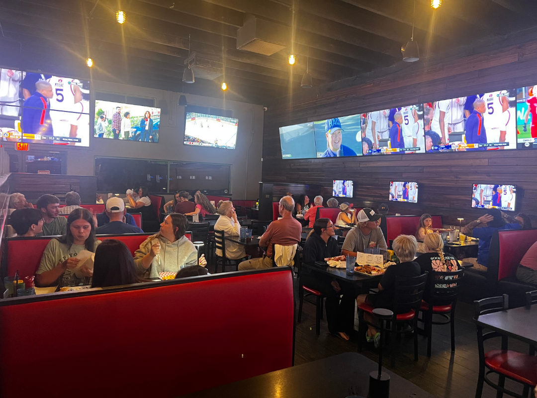Packed dining room with guests watching live sports on multiple large HD screens at Bogey's Sports Pub in Venice, FL, the best sports bar for NFL game-day viewing